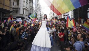 A participant wears a bridal dress as he waves the rainbow flag during a gay pride parade in central Istanbul