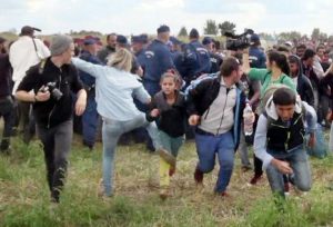 This video grab made on September 9, 2015 shows a Hungarian TV camerawoman kicking a child as she run with other migrants from a police line during disturbances at Roszke, southern Hungary. After the footage appeared, the camerawomen was fired on September 8 by N1TV, an internet-based TV station close to Hungary's far-right Jobbik party. The woman, later named as Petra Laszlo, can be seen tripping a man sprinting with a child in his arms, and kicking another running child in two separate incidents. The scenes took place as hundreds of migrants broke through a police line at a collection point close to the Serbian border where thousands have been crossing over each day for the past month.     AFP PHOTO / INDEX.HU