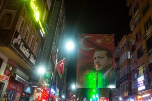 RIZE, TURKEY - OCTOBER 25:  A large flag of Turkish President Recep Tayyip Erdogan is seen hanging over a main street on October 25, 2016 in Rize Turkey. Although born in Kasimpasa, Istanbul, President Erdogan's family was originally from Rize a conservative town on the Black Sea. His family returned to Rize when Erdogan was very young staying until he was 13, before returning to Istanbul. Since the failed coup attempt on July 15, 2016 which saw 240 people killed including 173 civilians, Turkish authorities initiated a state of emergency, leading to an unprecedented crackdown on individuals and organizations with links to US-based cleric Fethullah Gulen and his organization blamed for instigating the uprising. The purge, targeting teachers, journalists, soldiers, judges, academics, police, military leaders, schools and universities has so far seen approximately 100,000 people dismissed, 70,000 detained, 32,000 arrested, 130 media outlets closed and some 15 universities shuttered. The failed coup and subsequent purge only appears to have further bolstered the president's popularity and increased nationalism across the country with July 15th having been marked as a new national holiday. Turkish flags, already prominently displaying all over have increased in numbers, as well as posters of those killed fighting the coup plotters appearing in train stations and public squares. The Bosphorus Bridge in Istanbul, which saw heavy fighting during the coup has been renamed the '15th July Martyr's Bridge'.  These changes, follow a year of instability in the country with constant terrorist attacks, an economic downturn, plummeting tourism, and a refugee crisis, all contributing to Turkish society undergoing its most dramatic restructuring in decades.  (Photo by Chris McGrath/Getty Images)