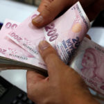 A money changer counts Turkish lira banknotes at a currency exchange office in Istanbul