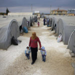 A Kurdish refugee woman from the Syrian town of Kobani keep warm at a refugee camp in the border town of Suruc